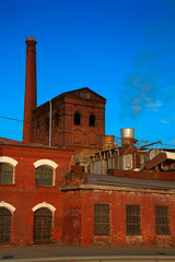 Fototapeta na wymiar brick buildings of an old factory with smoke coming from a chimney