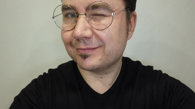 Portrait of an adult handsome man in glasses winks on a white background