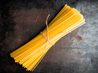 Raw dry spaghetti on the rustic wooden background. Selective focus.