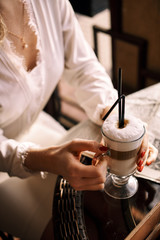 Fototapeta na wymiar A girl in a white dress, sits in a coffee shop and drinks her hot coffee. I took a coffee break.
