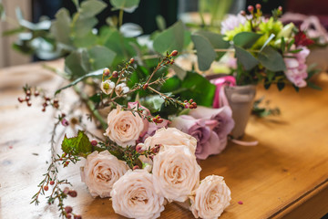 Florist collects a flower composition on the desktop. Spring bouquet of roses in pastel colors in a...
