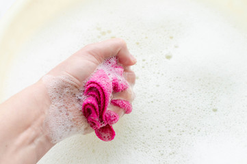 Household rag in hand on the background of soap suds. The concept of household.