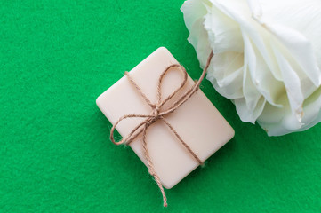 the soap is tied with a rope and a white rose on a green background with a place for the inscription. Concept of hygiene and Spa procedures.