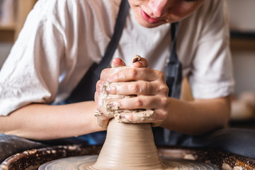 Potter working on a Potter's wheel making a vase. Woman forming the clay with hands creating jug in a workshop. Close up