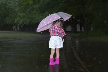 雨降りの暗い林を傘を差して歩く幼い女の子。孤独、虐待、一人ぼっちイメージ