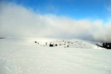 In Nebel geh&uuml;llter Feldberg im Schwarzwald. Schneebedecktes Skigebiet Feldberg mit Wolken und Sonne
