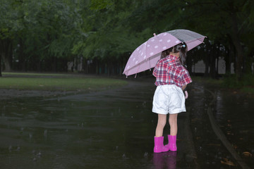 雨降りの暗い林を傘を差して歩く幼い女の子。孤独、虐待、一人ぼっちイメージ