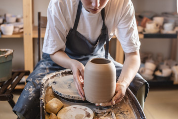 Woman potter working on a Potter's wheel making a vase. Master pulls the jug off the circle gently holding it in hands