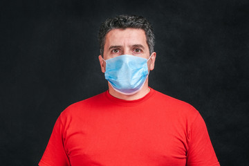 Portrait Middle aged caucasian man with medical protective face mask looking directly on camera.