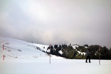 Wanderer mit Sonnenbrille am schneebedeckten Feldberg im Schwarzwald. Nebliger Hang des Berges mit Tannen im Hintergrund 