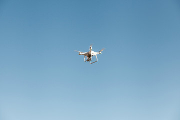A drone or quadrocopter flies against a blue sky. Modern technology for photographing and filming a bird's eye view.