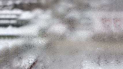 High humidity in the form of condensation on a transparent glass with large drops of natural water. Defective plastic window with condensation