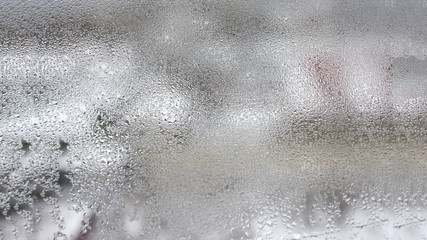 High humidity in the form of condensation on a transparent glass with large drops of natural water. Defective plastic window with condensation