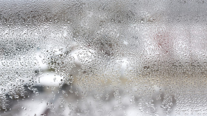 High humidity in the form of condensation on a transparent glass with large drops of natural water. Defective plastic window with condensation