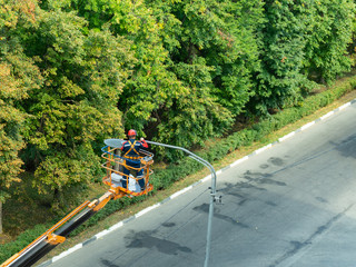 The specialist performs work on replacing old lamps on lampposts with new led lamps.