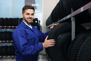 Obraz na płótnie Canvas Male mechanic with car tire in auto store