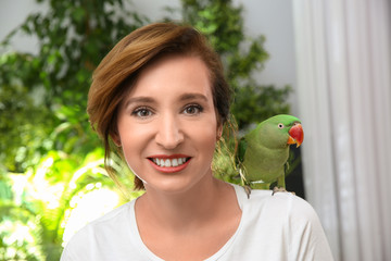Fototapeta premium Happy woman with Alexandrine parakeet on blurred background