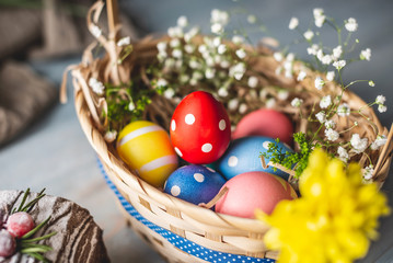 Festive Easter basket with colorful bright eggs on a wooden table. Traditional spring holiday