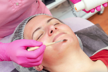 Beautician prepares patient for cosmetic mask, apply gel on face