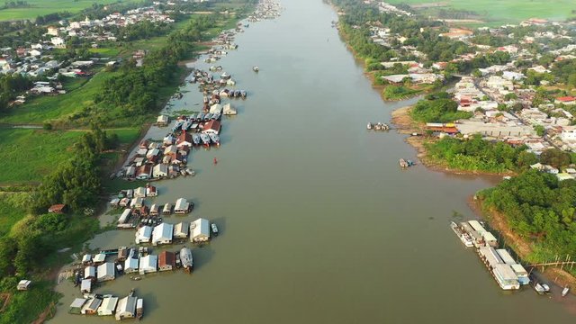 La rivi&egrave;re Bassac, le village flottant de Chau Doc et des rizi&egrave;res en arri&egrave;re plan &eacute;clair&eacute;s au coucher du Soleil dans le delta du M&eacute;kong, au sud du Vietnam