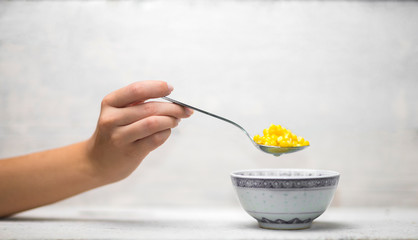 Hand holding spoonful of steamed corn