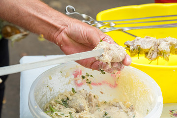 Man stringing marinated meat on skewer for barbecue