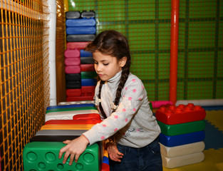 beautiful young girl enthusiastically plays in the children's play area