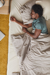 High angle view of African young man tired of hard day he sleeping in his bed in the bedroom