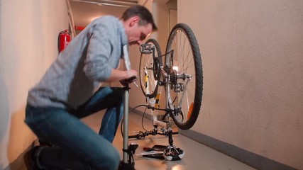 A man pumps up a wheel with a hand pump in a bicycle service.