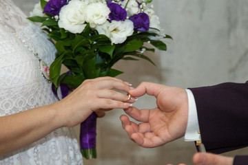 The bride and groom on their wedding day exchange wedding rings.