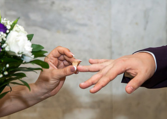 The bride and groom on their wedding day exchange wedding rings.