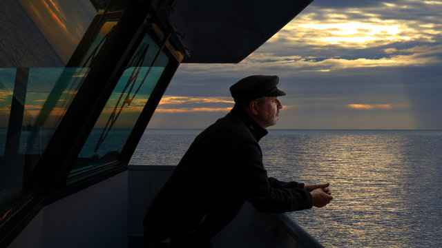 The captain of a cargo ship looks with satisfaction on the bridge towards the Mediterranean. It is an evening in February and the sun is low behind the clouds. Reflections on the water.
