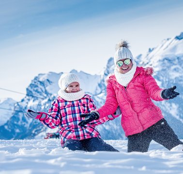 Zabawa z dzieckiem na sniegu w zimie we włoskich g&oacute;rach Dolomity na stoku narciarskim