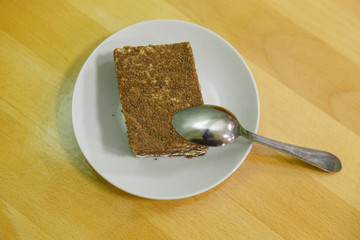  Cake on a saucer with a spoon on a yellow table