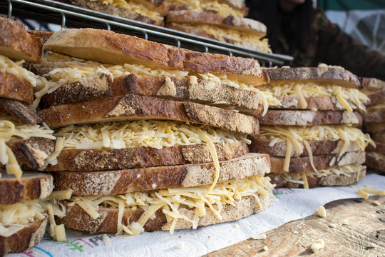 Rows of brown bread sandwiches with grated cheese for sale in a food hall.