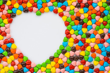 Valentine's card - heart-like small multi-colored candies form a colored background leaving a space for text in the shape of a large heart