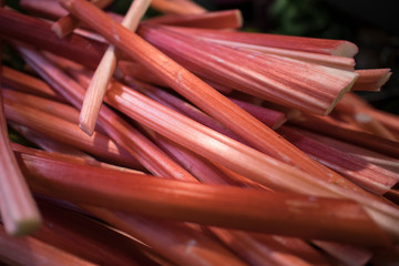 Red stalks of rhubarb are used for cooking jam and as filling for a pie. For sale on the counter.