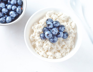 cottage cheese with blueberries on a white plate in a white bowl top view