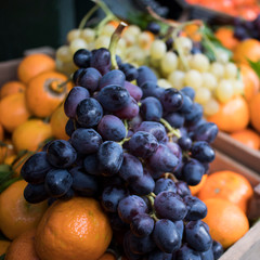 White and blue grapes on background of tangerines and oranges on a counter at Borough Market. Interior of a vegetable shop