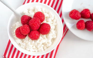 cottage cheese with raspberries on a white plate in a white bowl