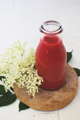 glass of strawberry juice and elder flower on wooden board