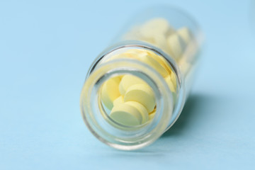 Minimalism style template for medical blog. Small glass bottle fwith small yellow pills spilled out blue background. Pharmaceutical concept. Medicine pills.