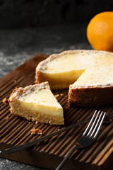Healthy wholegrain crust gluten free lemon pie on oak board on black background high angle view