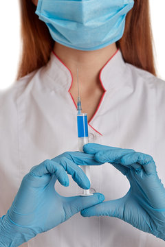 The doctor in a white coat on a white background holds a syringe with medicine in his hands. A nurse in a respiratory mask protects herself from the new rapidly spreading coronavirus. 