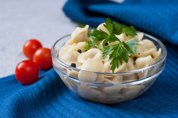 Russian pelmeni with parsley in a glass bowl