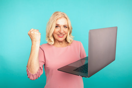 Portrait of happy exited abult lady with laptop isolated over the blue studio