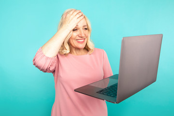 Portrait of happy exited abult lady with laptop isolated over the blue studio