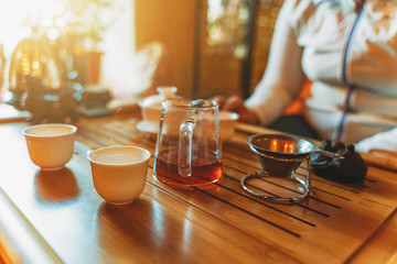 Chinese tea ceremony on wooden tea table in sunlight, selective focus.