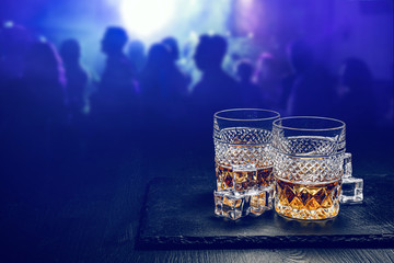 two expensive glasses of whiskey with ice on a black stone tray