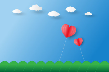 Fototapeta na wymiar two red heart shaped balloons float on blue sky under white clouds and over mountain